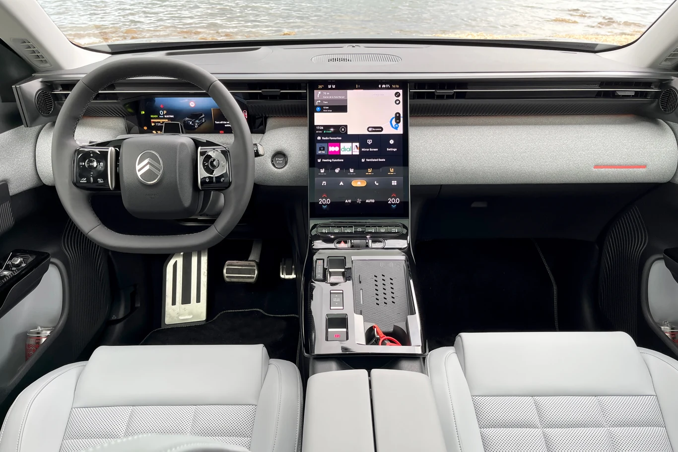 Kokpit nowego Citroena C5 Aircross prezentuje się bardzo atrakcyjnie. Nowoczesne wnętrze samochodu elektrycznego Citroën z cyfrowymi ekranami na desce rozdzielczej, minimalistycznym designem, dotykowym panelem sterowania oraz dwoma siedzeniami przednimi z jasnej tapicerki.