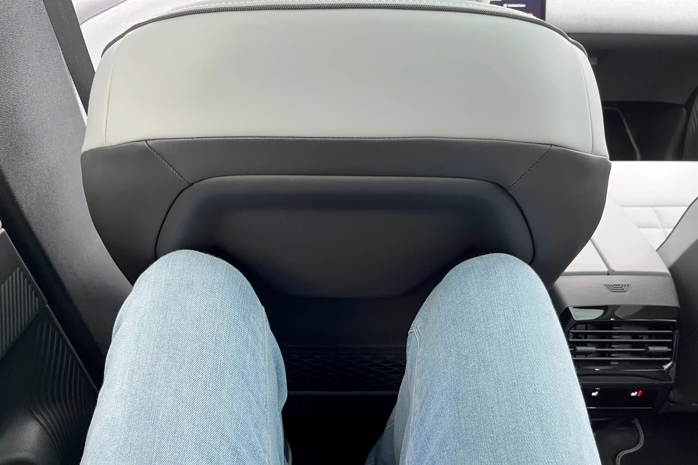 Z tyłu nawet wysokie osoby nie będą narzekały na brak miejsca na nogi. Nogi ubrane w jasne dżinsy znajdują się naprzeciwko tylnej części przedniego fotela samochodu, z widoczną przestrzenią na nogi i fragmentem podsufitki oraz kratką nawiewu.