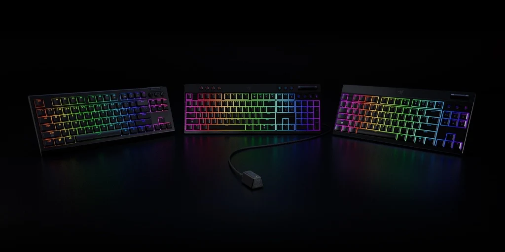 Trzy klawiatury mechaniczne z podświetleniem RGB prezentowane na tle czerni, centralnie z odłączonym przewodem USB, efektowne kolorowe światło rozświetla każdą klawiaturę w kilku barwach.