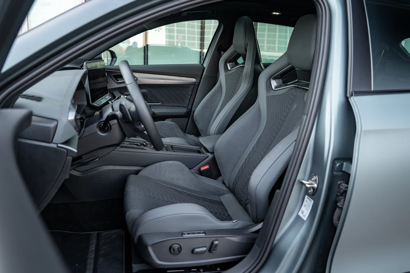 Nowoczesne wnętrze samochodu z dwoma sportowymi fotelami, czytelną deską rozdzielczą, ekranem multimedialnym i skórzanymi wykończeniami elementów.