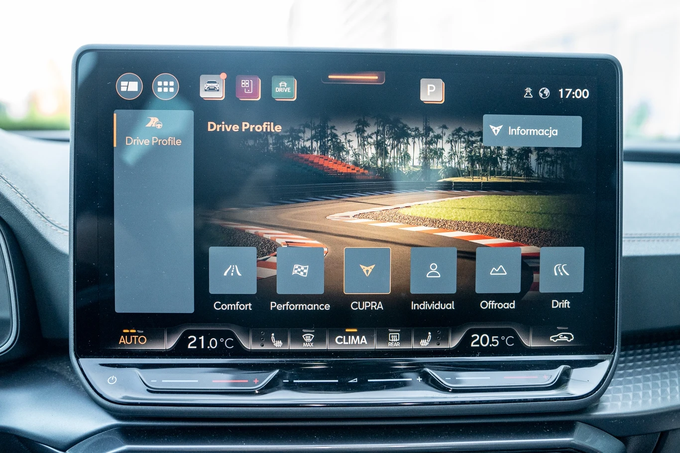 Duży ekran systemu multimedialnego samochodu wyświetlający menu wyboru profili jazdy, z widocznymi opcjami komfortu, trybu sportowego, indywidualnego oraz terenowego, a także ikonami nawigacji i parametrów klimatyzacji.