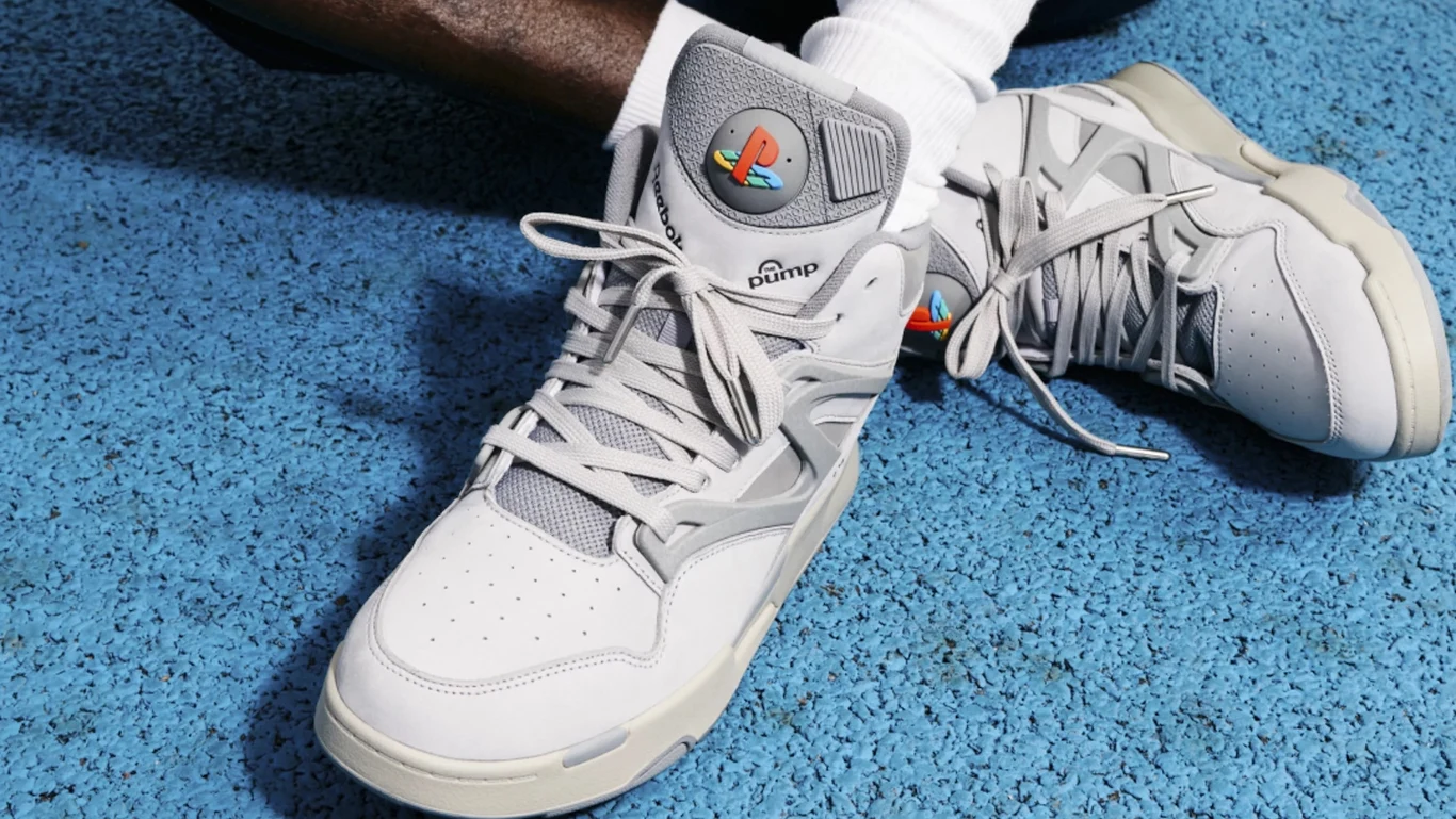 Sony nie przestaje zaskakiwać. Nowy merch z okazji 30-lecia istnienia marki PlayStation przyciągnie rzesze fanów Białe sneakersy marki Puma na nogach osoby ubrane w białe skarpetki, obuwie ustawione na niebieskiej nawierzchni sportowej.