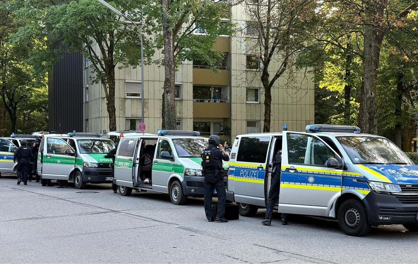 W Magdeburgu ogłoszono alarm. Zdjęcie ilustracyjne Szereg policyjnych radiowozów zaparkowanych przy ulicy z funkcjonariuszami w mundurach stojącymi przy pojazdach oraz w otoczeniu budynków mieszkalnych w tle, wokół drzewa i spokojna atmosfera.