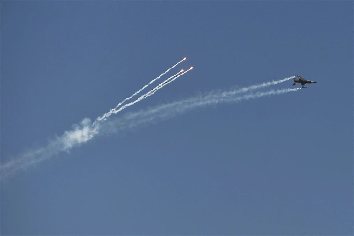 Indie zestrzeliły w maju pięć pakistańskich samolotów. Zdj. ilustracyjne Myśliwiec wojskowy wykonuje manewr na niebie, wypuszczając trzy flary, pozostawiając za sobą wyraźne ślady dymu na tle czystego, niebieskiego nieba