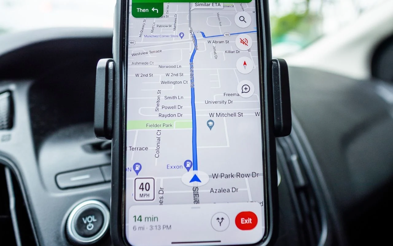 Smartfon zamocowany w samochodzie wyświetlający nawigację GPS z zaplanowaną trasą przejazdu oraz wskazaniami czasu i prędkości.
