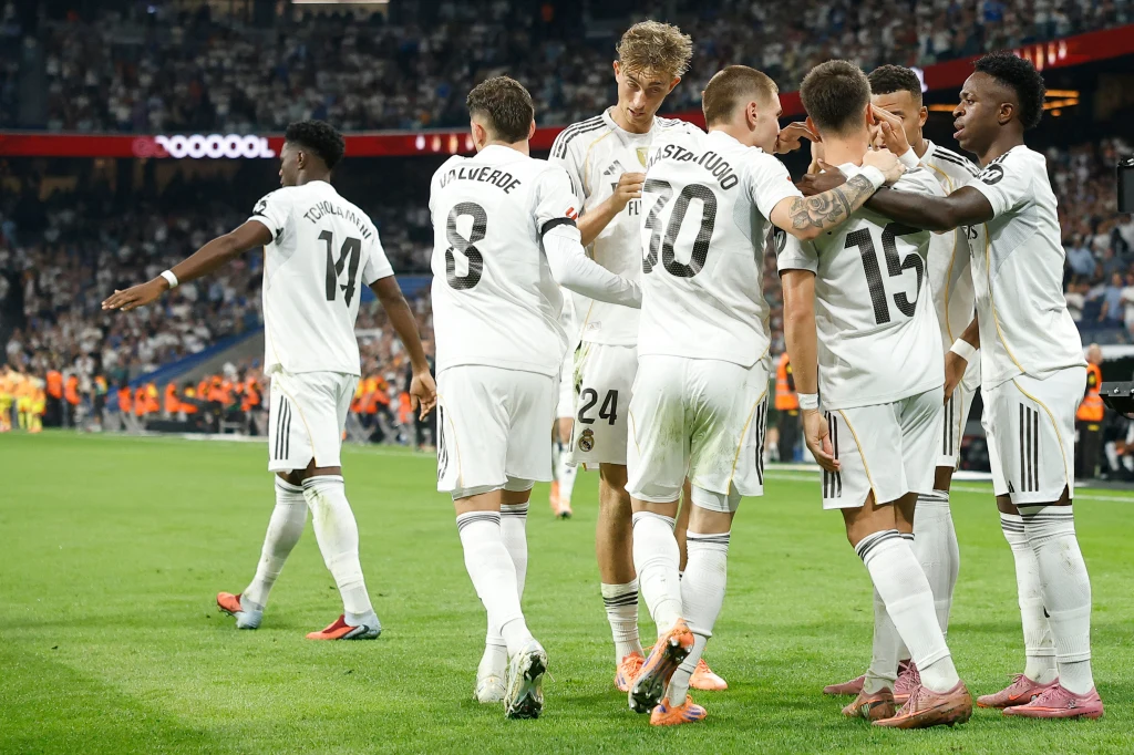 Real Madryt - Villarreal (4.10.2025) Grupa piłkarzy w białych strojach świętuje zdobycie gola na murawie stadionu podczas meczu przy pełnych trybunach kibiców.