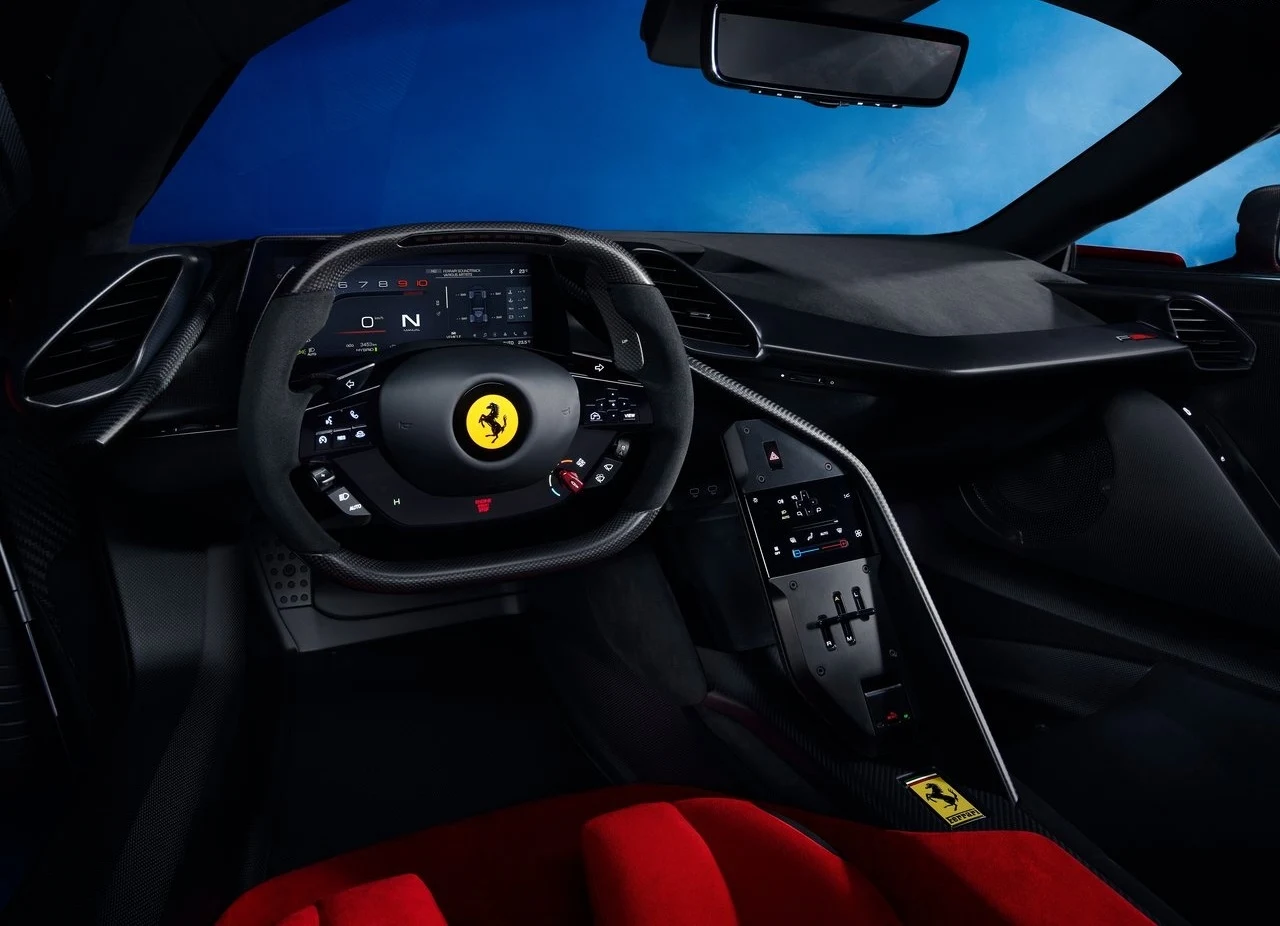 Kokpit luksusowego samochodu sportowego Ferrari z nowoczesnym panelem sterowania, cyfrowym wyświetlaczem, kierownicą z logo firmy oraz elementami wykończenia w kolorze czarnym i czerwonym.