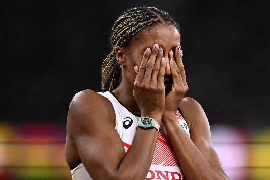 Nafissatou Thiam Zawodniczka w sportowym stroju zakrywająca twarz dłońmi, wyrażająca silne emocje, możliwie po zakończeniu rywalizacji sportowej na stadionie.