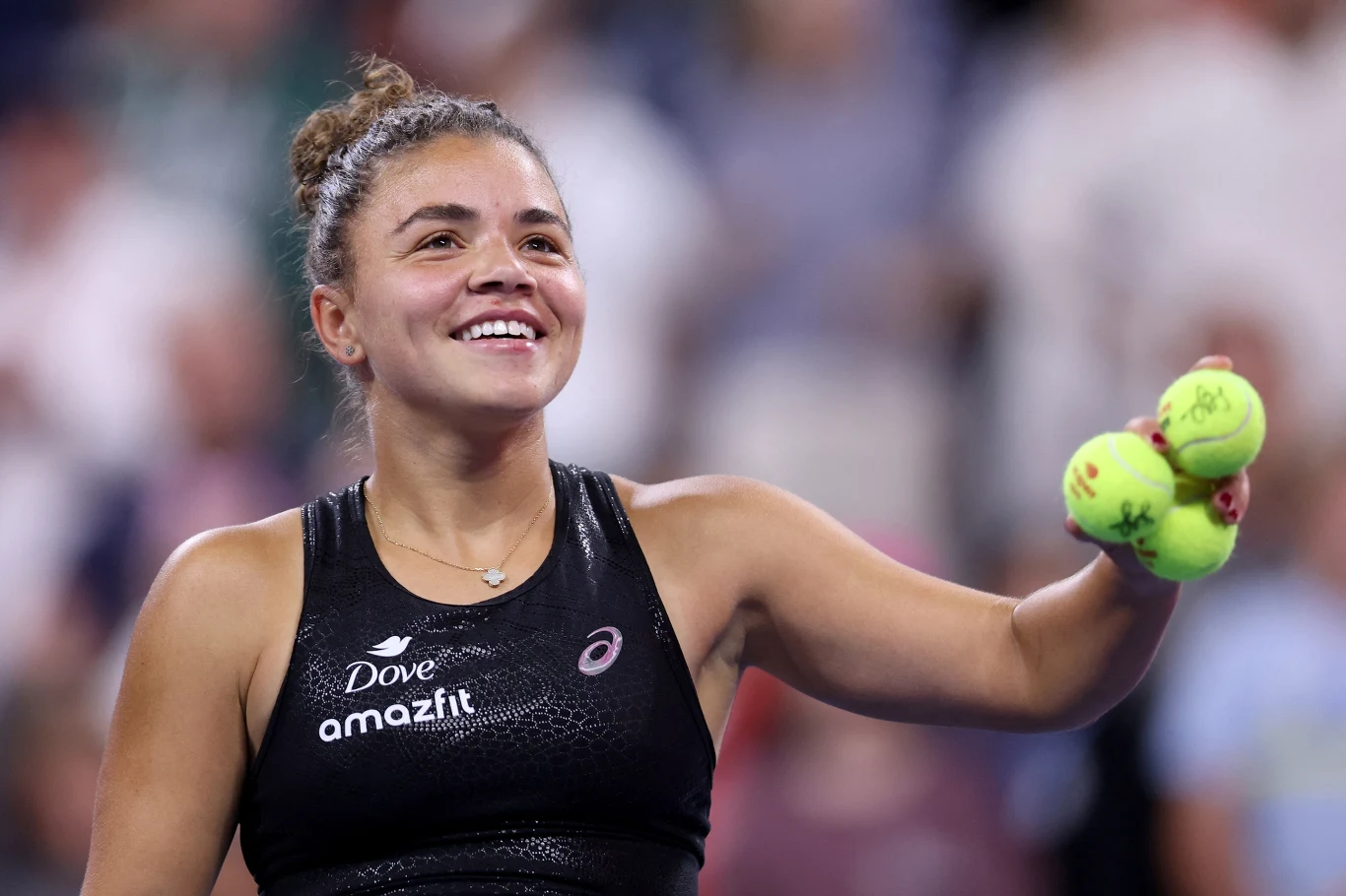 Jasmine Paolini awansowała do ćwierćfinału turnieju w Wuhanie Uśmiechnięta tenisistka w sportowym stroju trzymająca trzy piłki tenisowe na tle rozmytej publiczności.