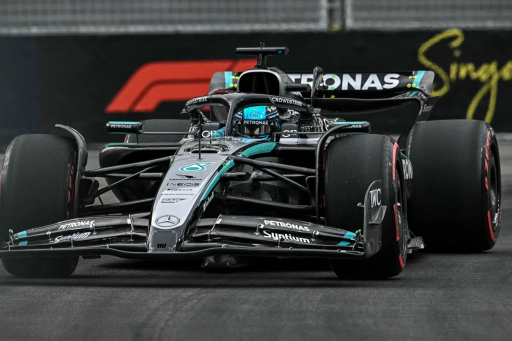 Bolid Formuły 1 zespołu Mercedes-AMG Petronas jadący po torze wyścigowym, z widocznym logotypem Grand Prix Singapuru w tle.