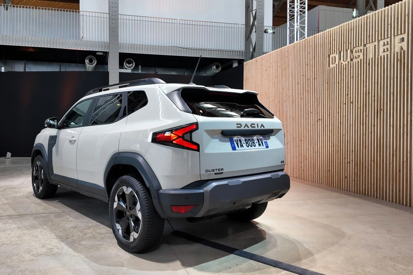 Nowoczesny, biały SUV marki Dacia Duster prezentowany w jasnym, przemysłowym wnętrzu, z widocznymi, wyrazistymi detalami tylnej części pojazdu i charakterystycznym oświetleniem.