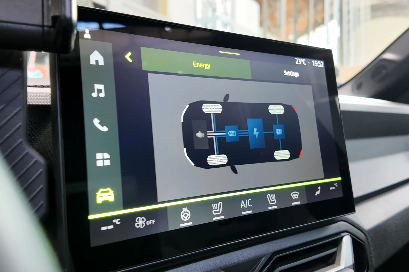 Wyświetlacz samochodu prezentuje schemat pracy układu napędowego samochodu elektrycznego, z zaznaczonym przepływem energii między silnikiem a kołami oraz ikonami różnych funkcji samochodu.