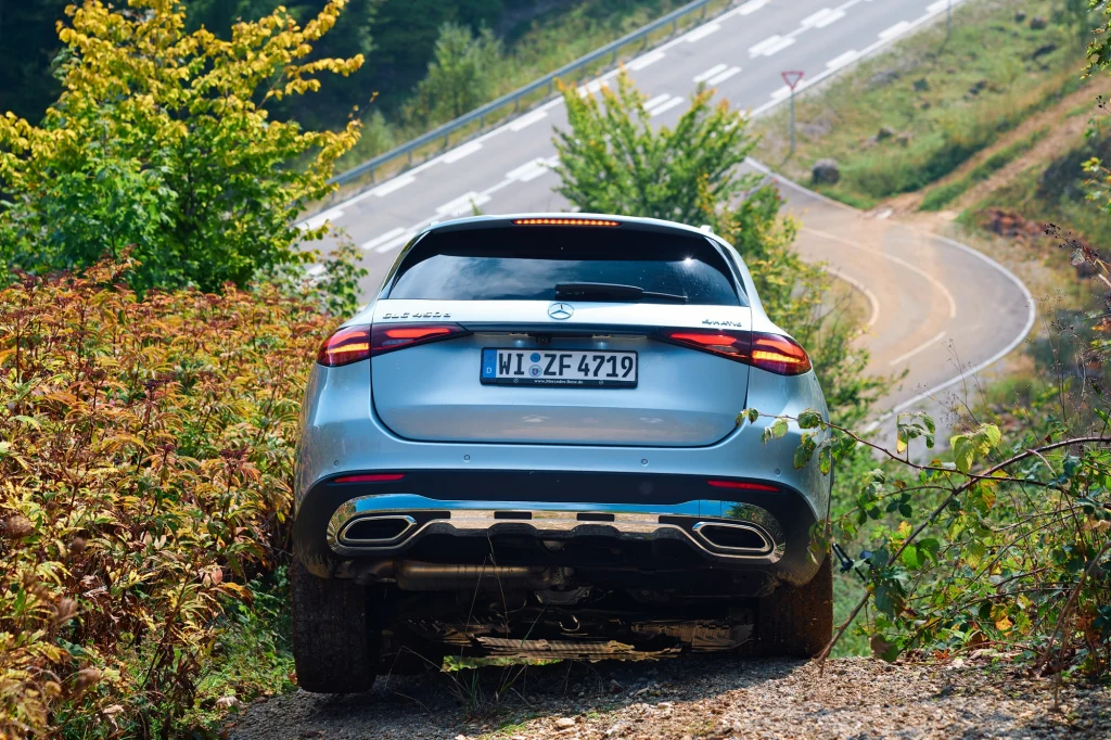 Chociaż ośrodek testowania samochodów kojarzy się raczej z asfaltem, to w Immendingen znajdziemy zaskakująco dużo terenów zielonych Luksusowy samochód terenowy marki Mercedes wjeżdża po stromym, żwirowym podjeździe pośród zielonych i brązowych krzewów, na drugim planie widoczna asfaltowa droga kręta wśród pagórków.