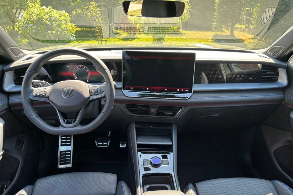 Nowoczesne wnętrze samochodu marki Volkswagen z dużym ekranem na konsoli centralnej, wielofunkcyjną kierownicą i minimalistycznym designem.