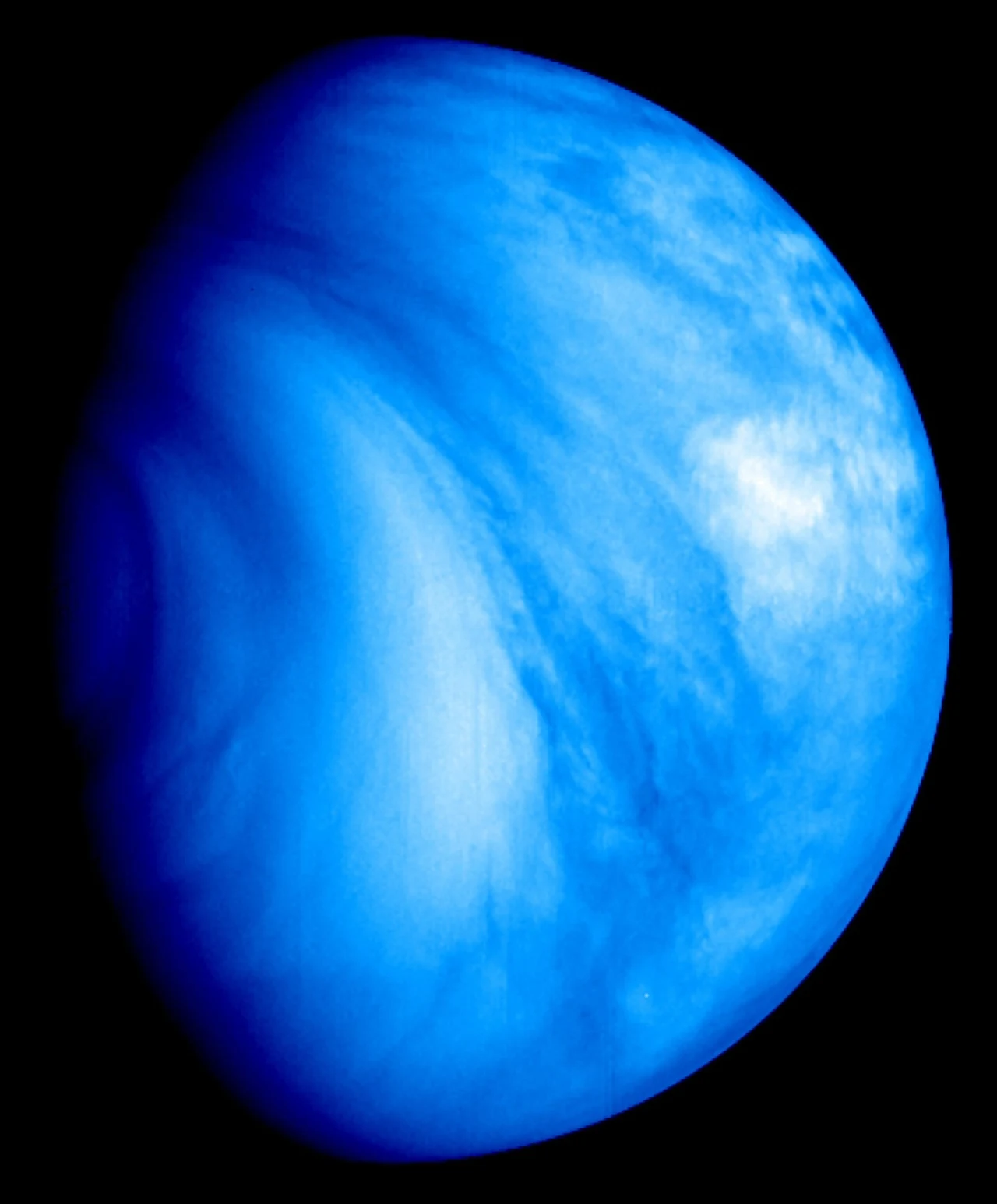 Obraz w sztucznym kolorze w paśmie UV wykonany przez sondę Venus Express ESA w 2007 r. Niebieska planeta z wyraźnie widoczną atmosferą i chmurami, sfotografowana na czarnym tle kosmosu; planeta zajmuje większość kadru.