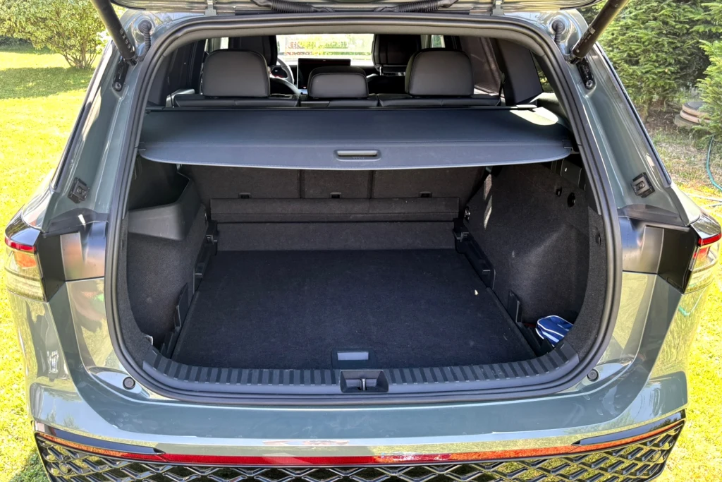 Otwarty bagażnik samochodu osobowego typu SUV z widoczną półką oraz przestronną, czystą powierzchnią ładunkową, w tle widoczne tylne siedzenia pasażerów.