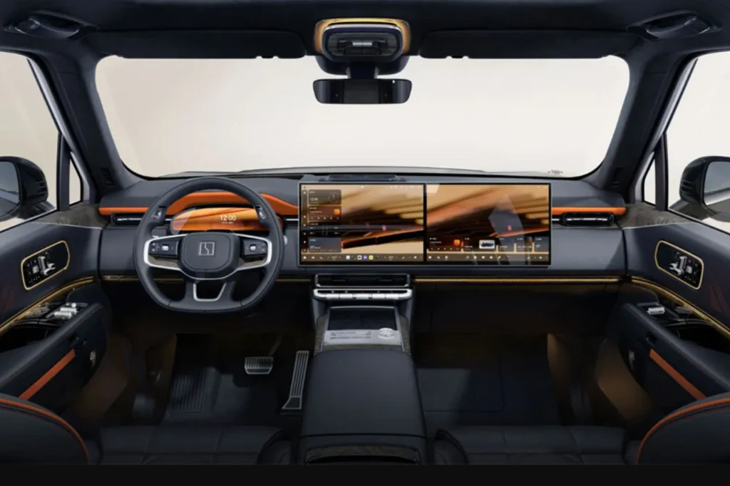 Wnętrze Zeekr 9X. Wnętrze nowoczesnego samochodu z cyfrową deską rozdzielczą wyposażoną w dwa szerokie ekrany dotykowe, stylowa kierownica z przyciskami, eleganckie wykończenia z pomarańczowymi akcentami oraz panoramiczny kokpit.