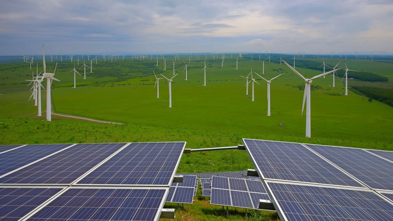 Koniec dominacji węgla w energetyce. OZE z rekordowym udziałem w produkcji energii Panele fotowoltaiczne i wiatraki na zielonej równinie, przedstawiające nowoczesne rozwiązania OZE