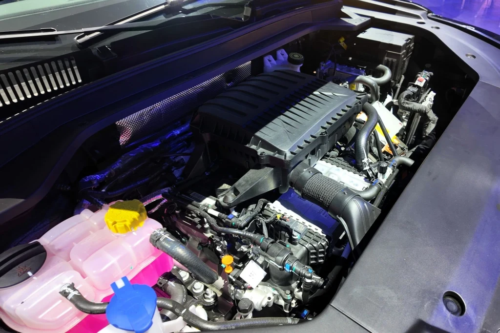 Hybryda plug-in Chery Tiggo 9 generuje 428 KM mocy systemowej. Komora silnika nowoczesnego samochodu, wyraźnie widoczne główne elementy jak jednostka napędowa, przewody, zbiorniki na płyny eksploatacyjne i elementy plastikowe osłaniające mechanizmy.