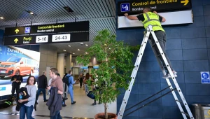 Pracownik zmienia znaki, aby kierować pasażerów lotów spoza strefy Schengen do nowo utworzonych punktów kontroli granicznej na terenie międzynarodowego lotniska Henri Coanda w Otopeni w Rumunii