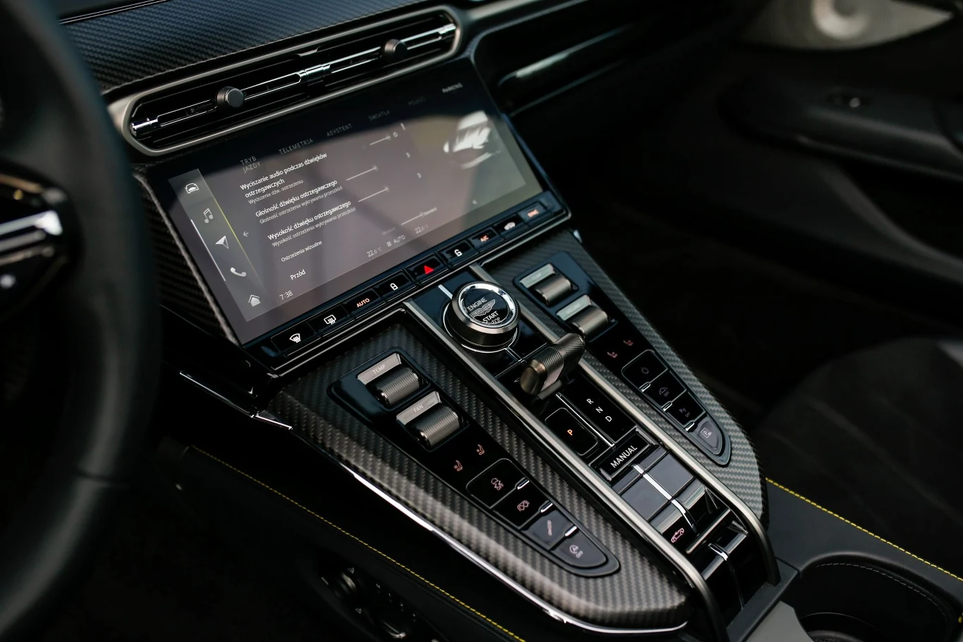 Do obsługi multimediów Astona Martina Vantage'a Roadstera służy 10,25-calowy ekran. Nie brakuje jednak również fizycznych przełączników. Panel sterowania nowoczesnego samochodu z dużym wyświetlaczem dotykowym, przyciskami do sterowania funkcjami pojazdu oraz wykończeniem z włókna węglowego.