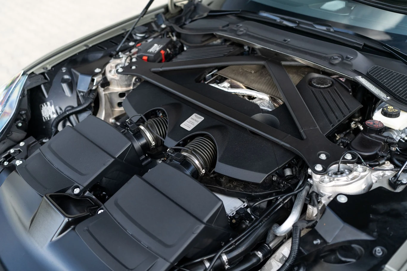 Czterolitrowy silnik V8 konstrukcji Mercedesa generuje 665 KM i 800 Nm. Komora silnika współczesnego samochodu osobowego z widocznymi komponentami mechanicznymi, przewodami oraz osłonami, a także elementem wzmacniającym konstrukcję nadwozia.