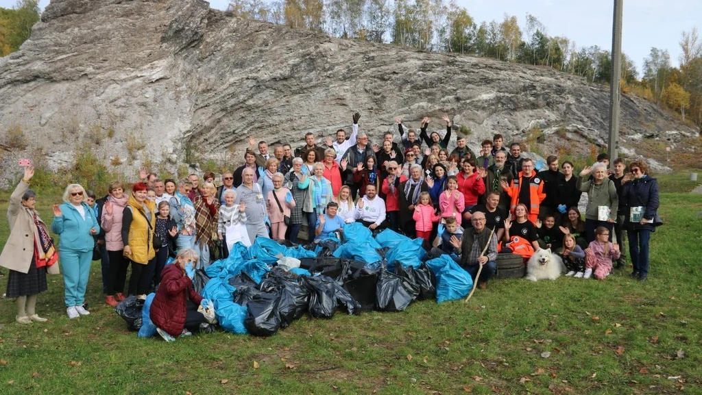 Aktywna i liczna grupa mieszkańców zaprezentowała efekty swojego zaangażowania fot. UM Starachowice Grupa ludzi różnych wiekowo stoi razem na tle skalistego wzgórza, przed nimi leży duża ilość niebieskich i czarnych worków z zebranymi śmieciami, wszyscy wyglądają na zadowolonych ze wspólnej akcji.