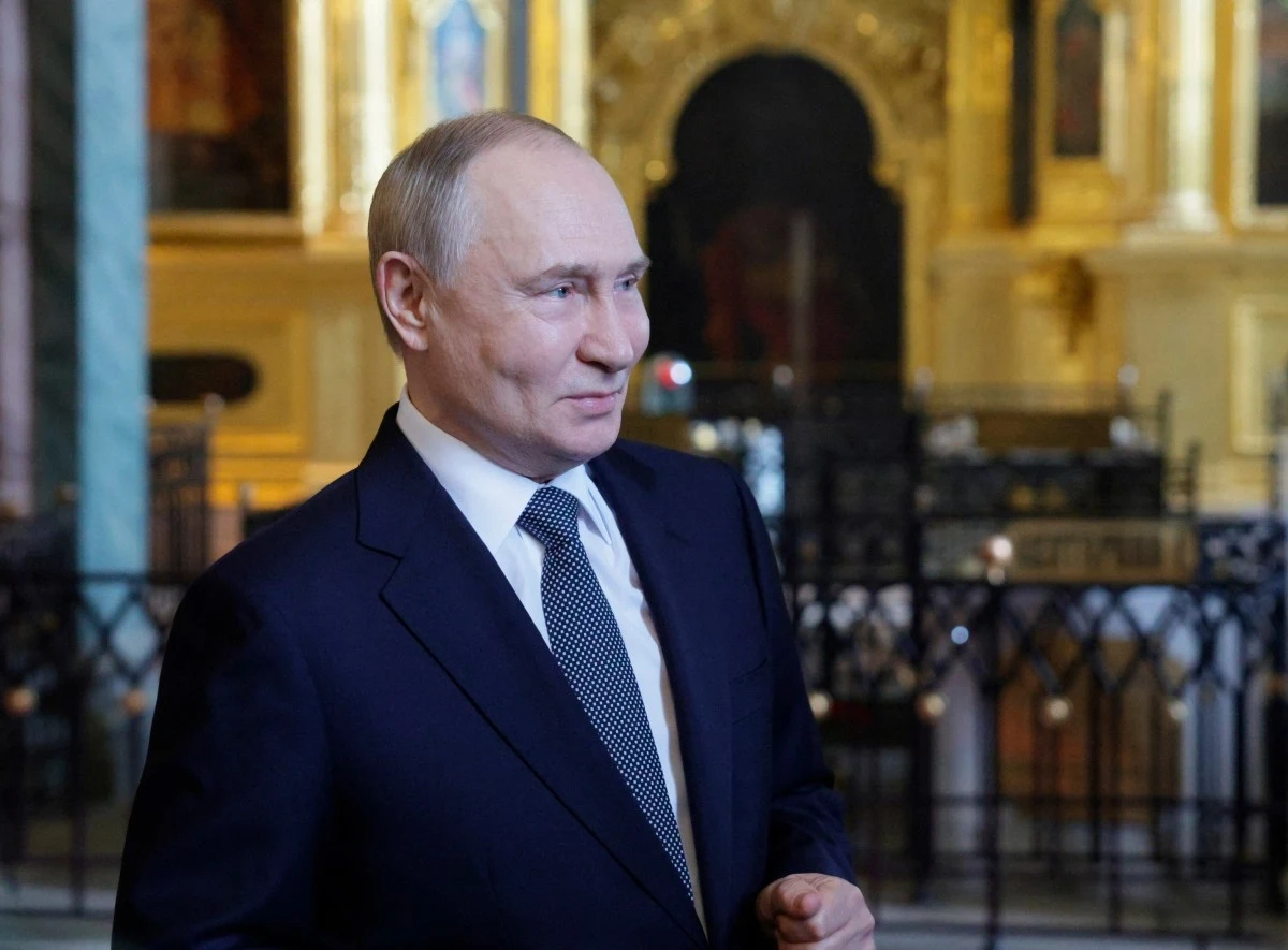 Władimir Putin Mężczyzna w garniturze i krawacie stoi na tle bogato zdobionego wnętrza z elementami architektury sakralnej i złoceniami.