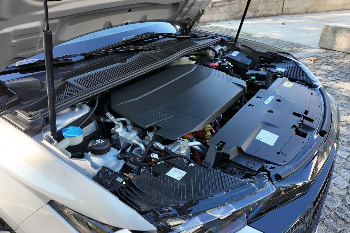 DS N4, w odróżnieniu od DS 4, będzie dostępne z napędem elektrycznym. Generuje 213 KM. Silnik samochodowy pod otwartą maską, widoczne elementy mechaniczne i pokrywa osłaniająca silnik, po lewej stronie pojemnik na płyn chłodniczy.