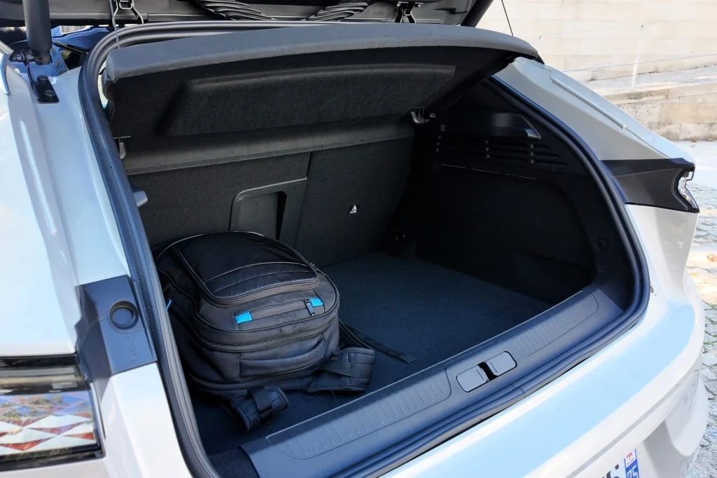 Otwarty bagażnik samochodu z widocznym czarnym plecakiem leżącym na podłodze przestrzeni bagażowej, wnętrze zadbane i uporządkowane.