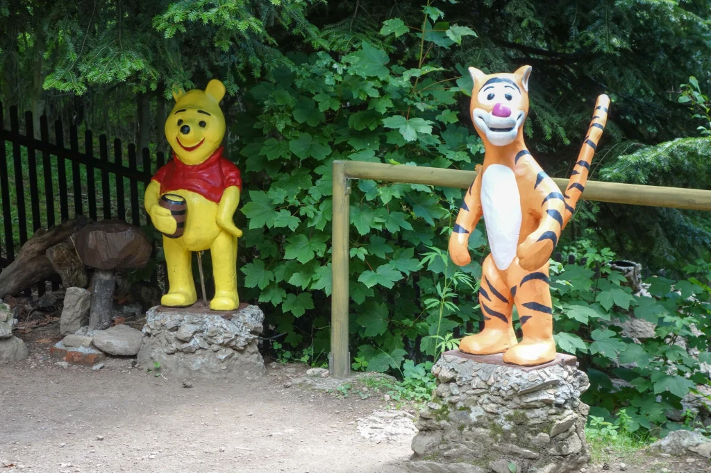 Będąc w Międzygórzu, warto odwiedzić malowniczo położony Ogród Bajek, w którym kryją się ukochane postaci z filmów animowanych Kolorowe figury Kubusia Puchatka oraz Tygryska stojące na kamiennych podstawkach w otoczeniu zielonych krzewów i drzew w parku lub ogrodzie.