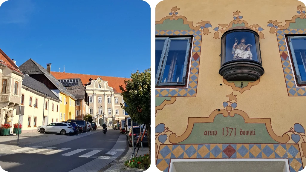 Kolorowa elewacja budynku z ozdobnymi detalami i figurką religijną w niszy, napisem 'anno 1371 domini' oraz fragment miejskości z ulicą, zaparkowanymi samochodami i zabytkowymi kamienicami pod błękitnym niebem.