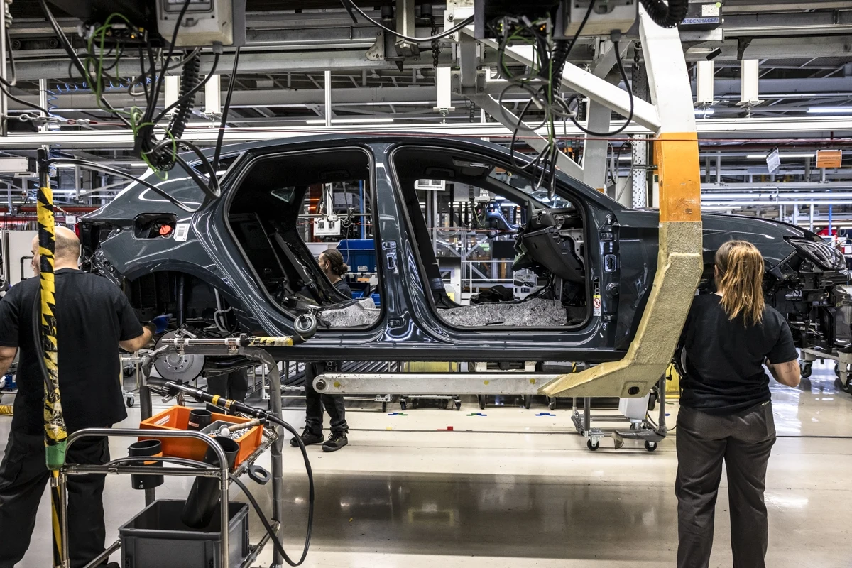 Ograniczenia eksportu metali ziem rzadkich wprowadzone przez Chiny to problem m.in. dla producentów samochodów Montaż karoserii samochodu na linii produkcyjnej w fabryce, pracownicy skupieni przy pracy z zaawansowanymi maszynami i narzędziami, jasne oświetlenie oraz widoczne detale konstrukcyjne pojazdu.