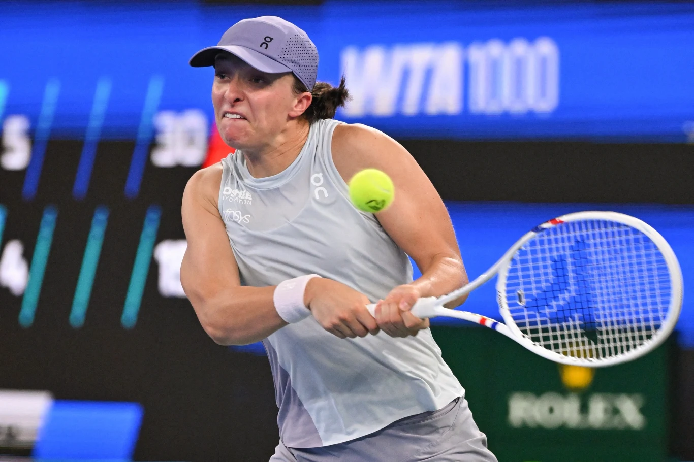 Iga Świątek w trakcie turnieju WTA 1000 w Wuhan 2025 Zawodniczka tenisowa w dynamicznej akcji podczas meczu na korcie, skupiona na odbiciu nadlatującej piłki, ujęcie podkreślające sportowe emocje i wysiłek.