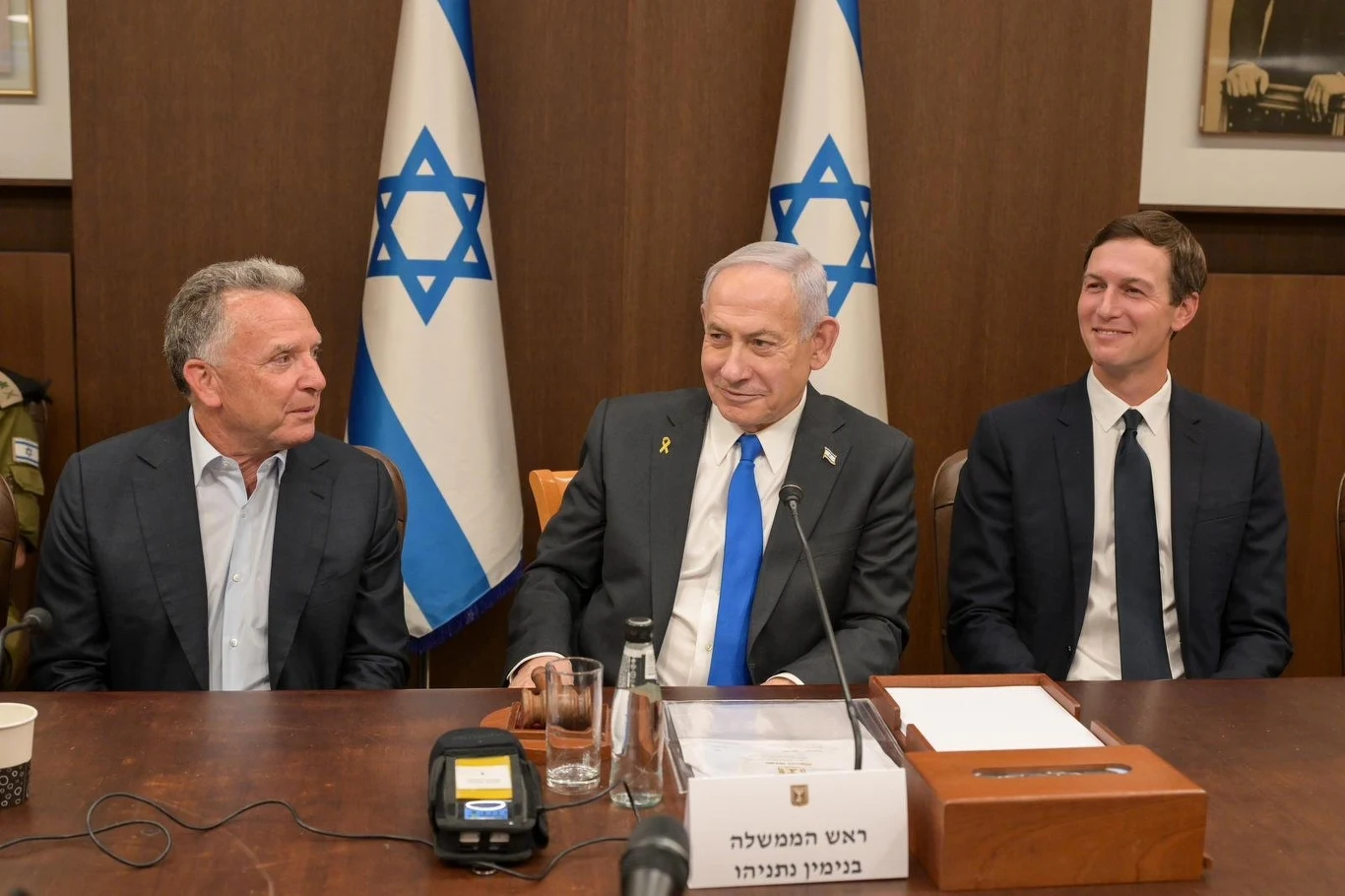 Rząd Izraela ratyfikował porozumienie z Hamasem Trzech mężczyzn siedzących przy konferencyjnym stole, w tle rządowe flagi Izraela, na stole mikrofon oraz tabliczka z napisem po hebrajsku, atmosfera oficjalnego spotkania politycznego.