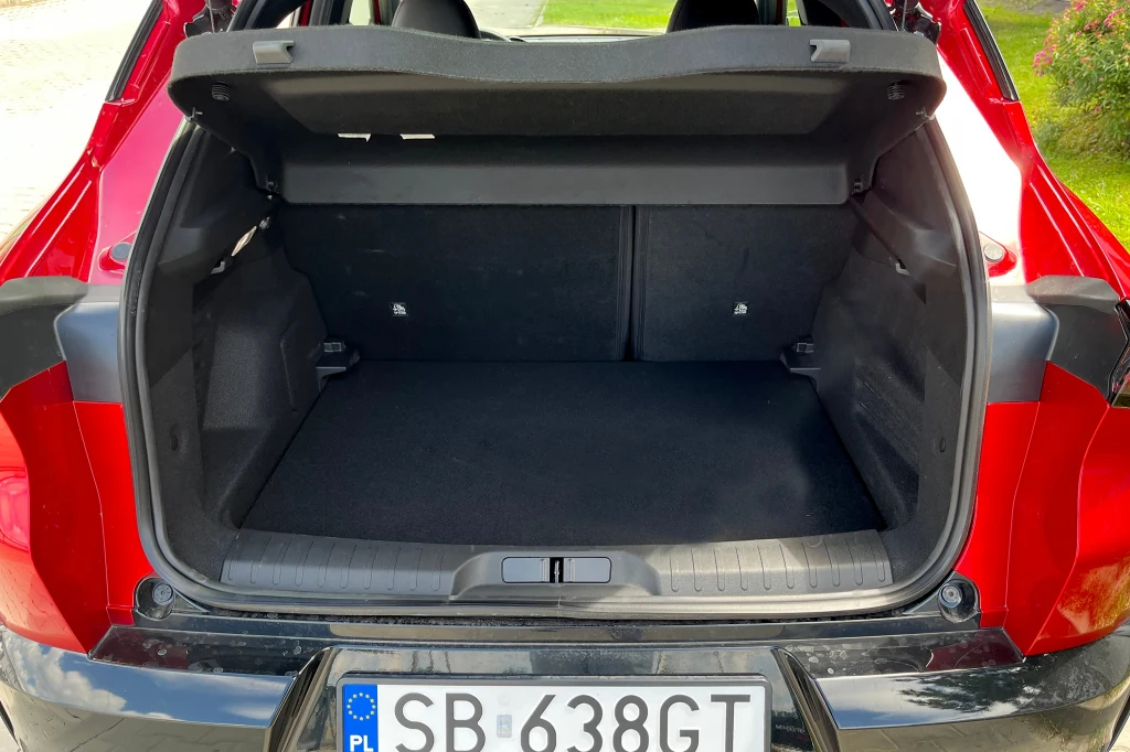 Otwarty bagażnik czerwonego samochodu osobowego z widoczną przestrzenią ładunkową oraz numerem rejestracyjnym SB 638GT.
