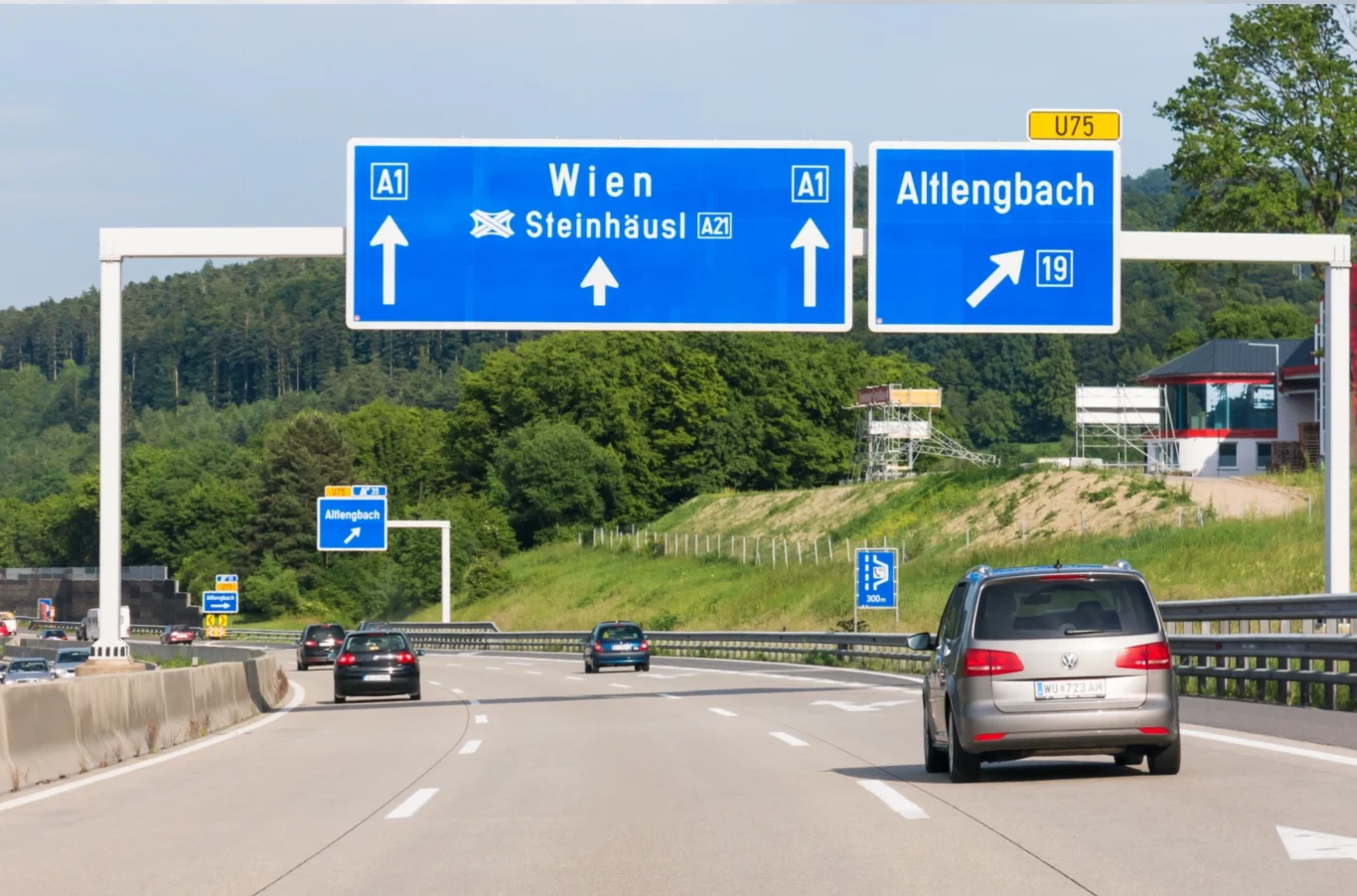 Ile kosztują autostrady w Austrii? Nowe ceny winiet od 2026 r. Autostrada z kilkoma samochodami jadącymi w kierunku Wiednia i Attlengbach, niebieskie znaki drogowe nad jezdnią wskazujące kierunki podróży, otoczenie z zielonym lasem i lekkim wzniesieniem w tle.