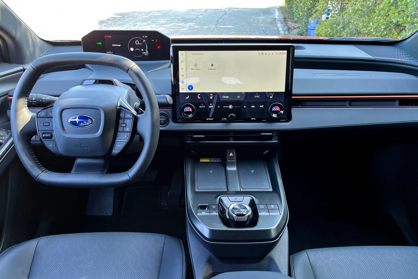 Widok na nowoczesną deskę rozdzielczą samochodu Subaru z dużym ekranem dotykowym na środku, wielofunkcyjną kierownicą oraz cyfrowym panelem wskaźników.