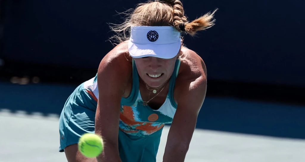 Magdalena Fręch Kobieta w sportowym stroju oraz białej czapce z daszkiem wykonuje zagranie tenisowe na korcie, skupiając wzrok na lecącej piłce tenisowej.