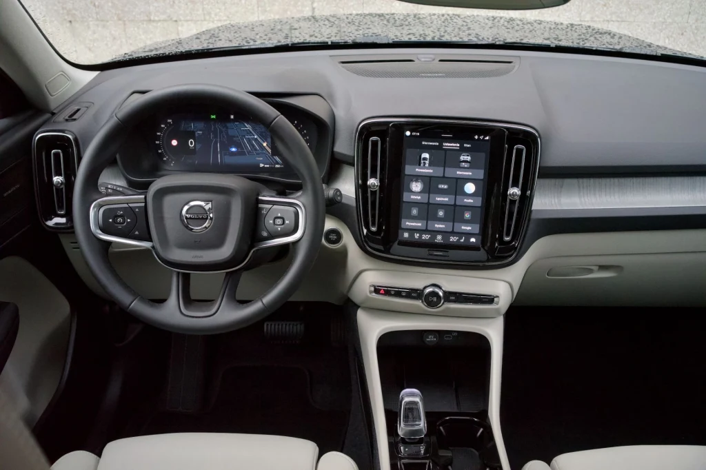Wewnątrz Volvo XC40 znajdziemy dwa wyświetlacze: 12,3-calowy ekran wskaźników i 9-calowy do obsługi multimediów. Kokpit nowoczesnego samochodu marki Volvo z dużym, dotykowym ekranem centralnym, cyfrowymi wskaźnikami za kierownicą oraz eleganckim wykończeniem deski rozdzielczej.