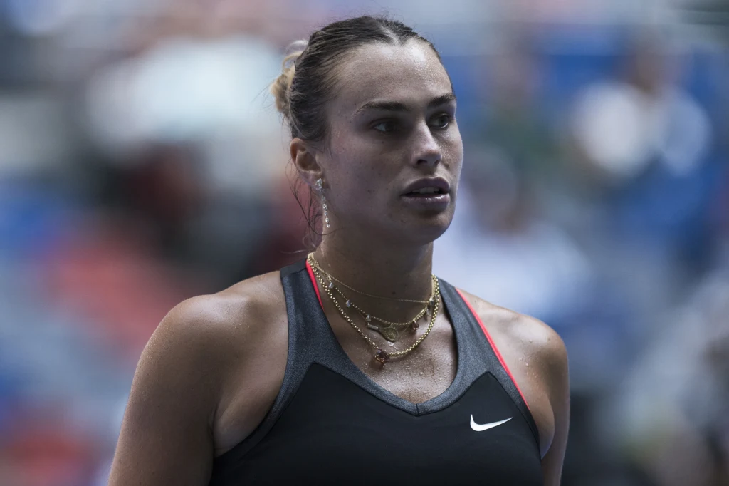 Aryna Sabalenka rywalizowała z Jessicą Pegulą o finał WTA 1000 w Wuhan Tenisistka w sportowym stroju na tle rozmytego stadionu, widoczne naszyjniki, skupiony wyraz twarzy, włosy związane do tyłu.