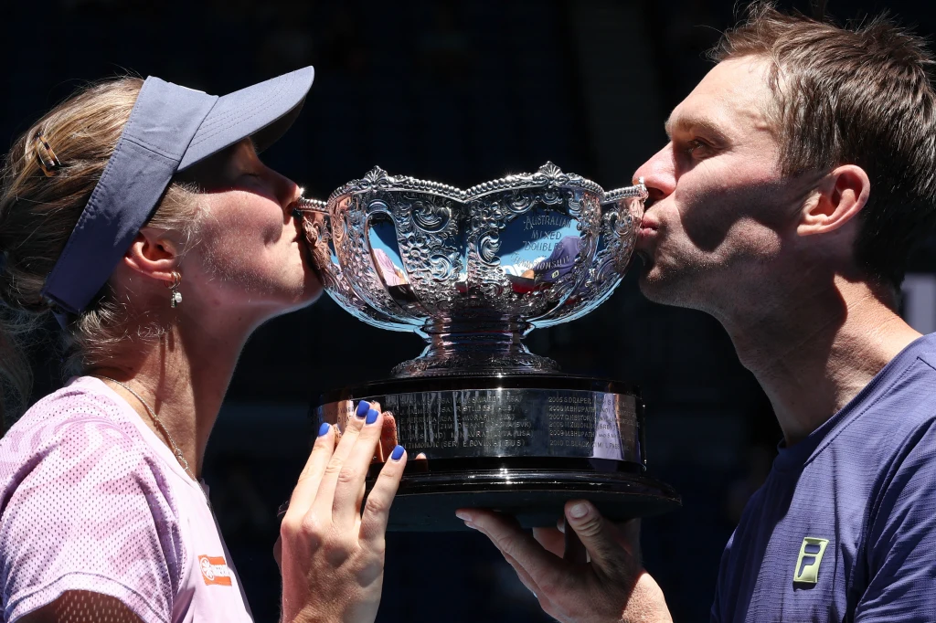 Olivia Gadecki i John Peers po wygraniu Australian Open Dwoje sportowców całuje duży srebrny puchar, najprawdopodobniej po wygranym turnieju tenisa, oboje ubrani w stroje sportowe, trofeum na pierwszym planie.