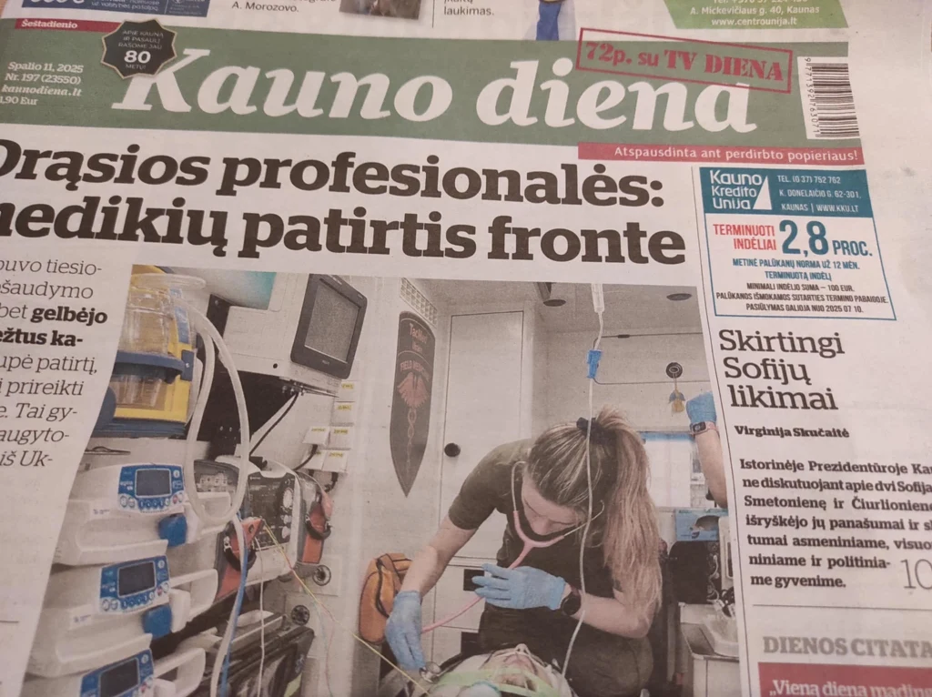 Lekarka w rękawiczkach i masce zajmuje się pacjentem podłączonym do aparatury medycznej w szpitalnym otoczeniu, na pierwszym planie widoczne są monitory i sprzęt medyczny.