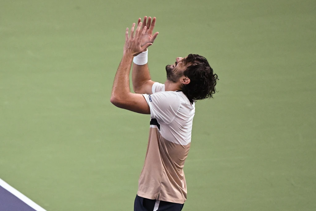 Valentin Vacherot Zawodnik tenisa na korcie unosi ręce do góry, wyrażając silne emocje, prawdopodobnie radość lub ulgę po zakończonym meczu.