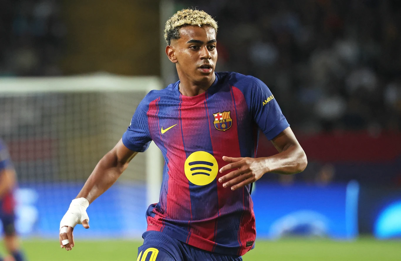 Piłkarz w koszulce FC Barcelona biegnący po murawie podczas meczu, skupiony wzrok, ruch na boisku, rozpoznawalne logo klubu na stroju.