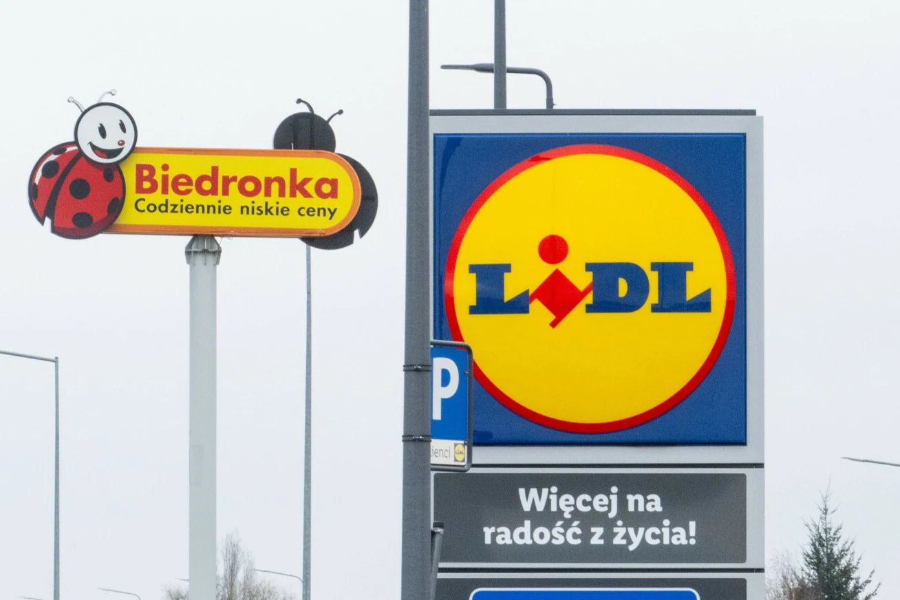 Lidl i Biedronka przygotowały specjalne oferty dla kierowców i lubiących majsterkować. Tablice reklamowe dwóch popularnych sieci supermarketów, Biedronka i Lidl, ustawione obok siebie na tle szarego nieba, z wyraźnie widocznymi logotypami i hasłem promocyjnym pod szyldem Lidla.