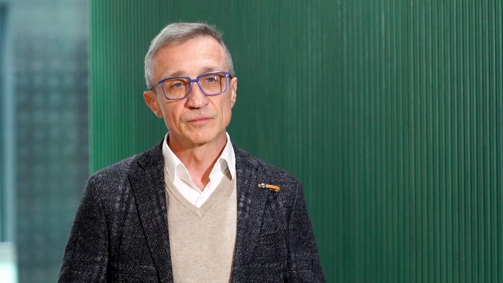 Newseria - Andrzej Sowa, dyrektor odpowiedzialny za kredyty i ubezpieczenia dla klientów indywidualnych ING Bank Śląski Mężczyzna w średnim wieku w okularach, elegancko ubrany w marynarkę i sweter, stoi na tle zielonej ściany.