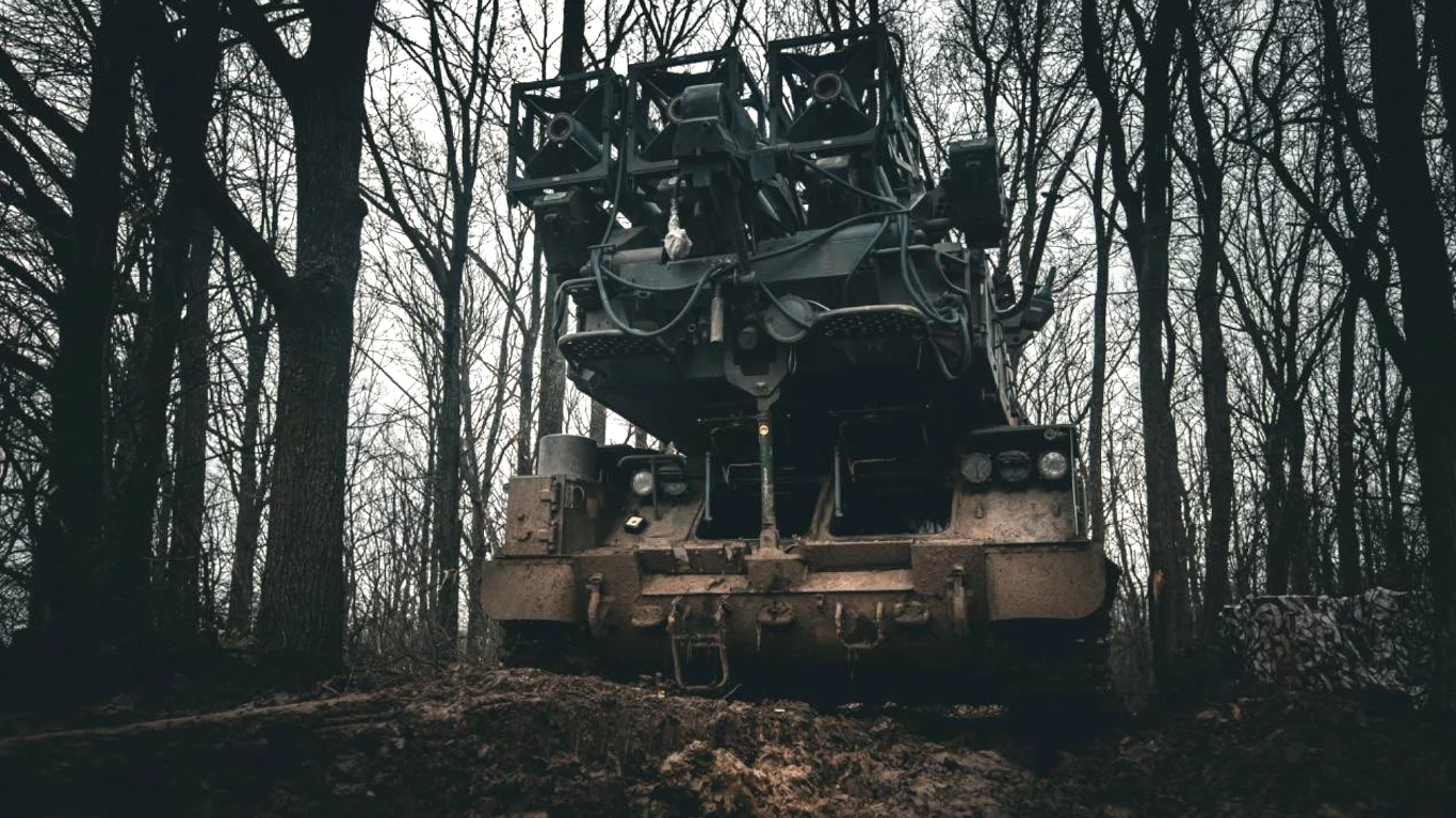 Ukraińcy pokazali wyrzutnię FrankenSAM. Aby powstała musieli zainterweniować Amerykanie Wojskowy pojazd opancerzony wyposażony w zaawansowany system rakietowy, ustawiony na leśnej polanie wśród wysokich, nagich drzew, przy ponurym, pochmurnym niebie.