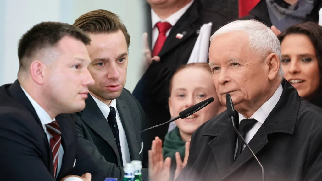 Grupa ludzi w eleganckich garniturach przy stole, jeden z mężczyzn przemawia do mikrofonu, wokół zgromadzeni słuchacze, atmosfera oficjalnego spotkania lub debaty.