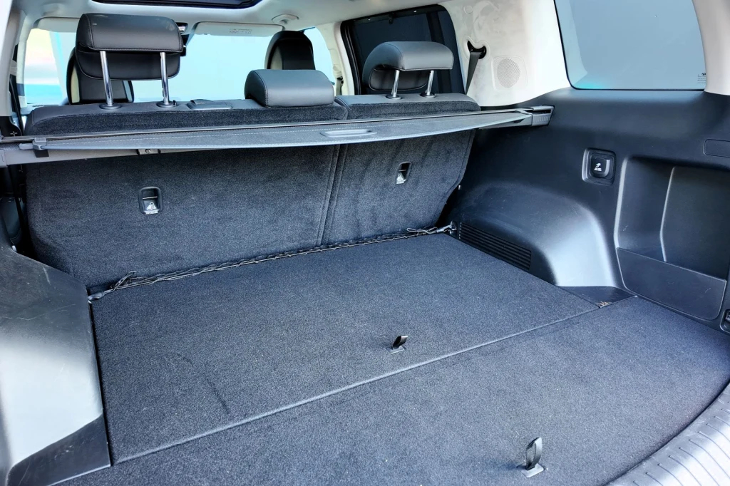 Przestronny bagażnik samochodu z rozłożoną podłogą i osłoną, o nowoczesnym wykończeniu i składanych tylnych siedzeniach podnoszących funkcjonalność auta.